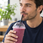 Voksen drikker smoothie med sort lige sugerør gennem kuppellåg