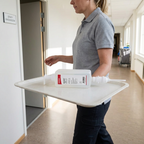 Medarbejder bærer Katrin Ease refill på servicebakke ved personaletoilet