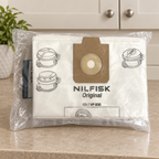 Miljøbillede af Nilfisk-fleeceposer på beige bord foran skab