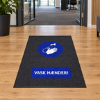 Vask Hænder-smudsmåtte på trægulv ved kontorindgang, genereret miljøbillede