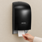 Sort Katrin-toiletrulledispenser i brug på beige væg