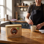 Voksen medarbejder rører kaffe i personaleområdet med Nescafé Gold Blend 500 g i forgrunden