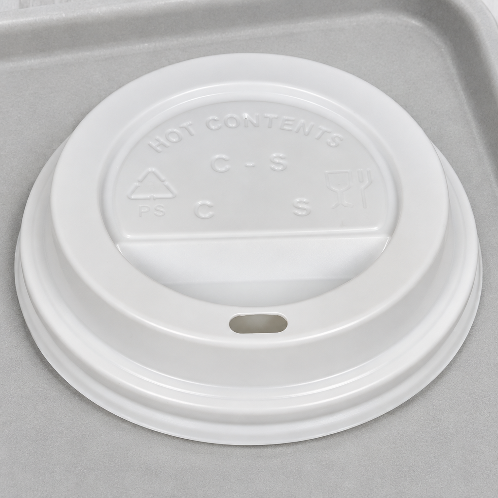 Detalje af hvidt låg med drikkehul på cafébakke