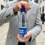 Blåt låg drejes på en håndholdt 0,5-liters logovandsflaske ved et udendørs arrangement
