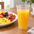 Klart PP-drikkeglas med appelsinjuice ved morgenbord