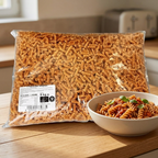 Pose med fuldkornspastaskruer 5 kg ved en skål pasta med tomatsauce