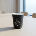 Tomt sort kaffebæger med kaffekopmotiv på lyst mødebord