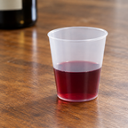 Translucent PP-shotglas med rød vinsmagsprøve på træbord, stemningsbillede