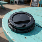 Sort drikkelåg på turkis cafébord i solskin