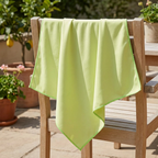 Grøn mikrofiber-glasklud over stoleryg på solrig terrasse
