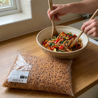 Pastasalat med fuldkornsfusilli blandes ved den gennemsigtige pastapose