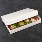 Smørrebrød i hvid rektangulær kartonæske på mørk bordflade