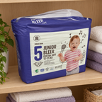 Rema 1000 Junior 5 blepakke til 12–25 kg på træhylde med foldede håndklæder
