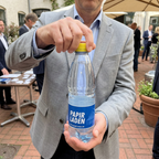 Gult låg drejes på en håndholdt 0,5-liters logovandsflaske ved et udendørs arrangement
