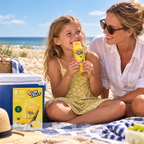 Barn og forælder nyder Sun Lolly Ananas på picnictæppe ved stranden