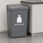 Hvid restaffaldsmærkning på grå beholder ved køkkenbord