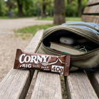 Corny Milk Dark & White 40 g ved rygsæk på parkbænk, stemningsbillede