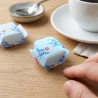 Indpakkede sukkerknalder ved kaffekop på træbord