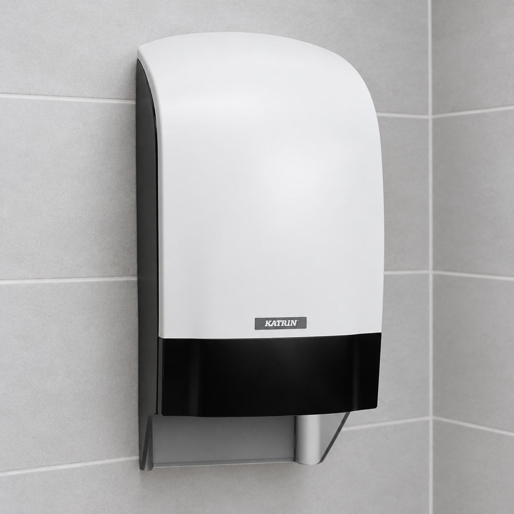 Katrin-toiletrulledispenser med hvid front og sort panel på grå fliser
