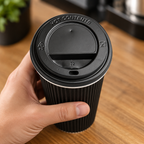 Sort låg med drikkehul på Ripple-kaffebæger ved caféens disk