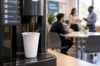 Kaffeautomat der fylder et automatbæger på et kontor