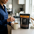 Voksen rører kaffe i kop ved Café Noir Medium 240 g-pose