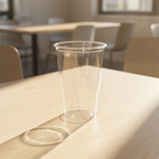 Tomt klart plastglas på et solbeskinnet kantinebord