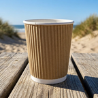 Brunt kaffebæger på træbord ved solrig strand