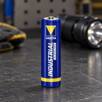 Varta Industrial AA-batteri på mørkt arbejdsbord ved lommelygte