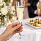 Champagneglas i klar plast med fast fod holdt ved stilken under reception