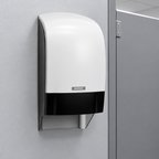 Hvid Katrin-toiletrulledispenser ved skillevæg i toiletrum