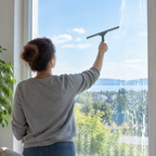Stemningsbillede af vinduespudsning med generisk skraber, ikke foto af konkret vinduesskraber