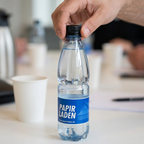 Det sorte låg drejes ved åbning af Papirladens 0,5-liters logovand ved kaffepausen
