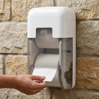 Voksen hånd tager toiletpapir fra hvid Tork OptiServe T7-dispenser med ét papirudtag