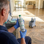 Medarbejder med handsker læser etiketten på Kiehl Ambital-eco balance 1 L ved lys indgang