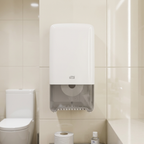Hvid Tork T6 Twin-dispenser ved toilet på cremefarvede fliser