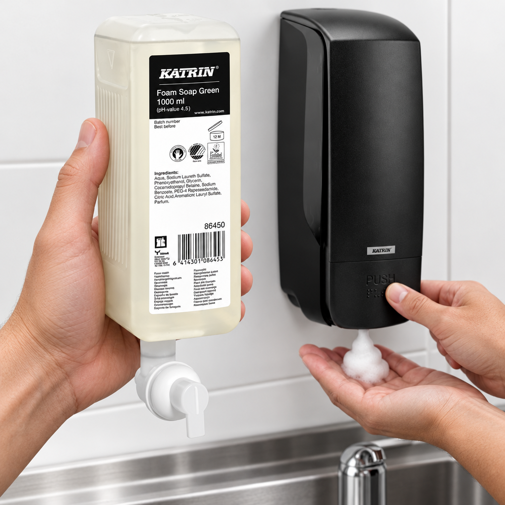 Katrin Green 86450 skumsæberefill i forgrunden med sort Katrin 77397-dispenser i brug ved håndvask