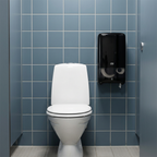 Sort Tork T6 Twin-dispenser ved toilet på blågrå flisevæg