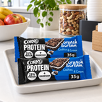 Stemningsillustration af portionspakkede Corny Protein Cookies & Cream barer på serveringsbakke